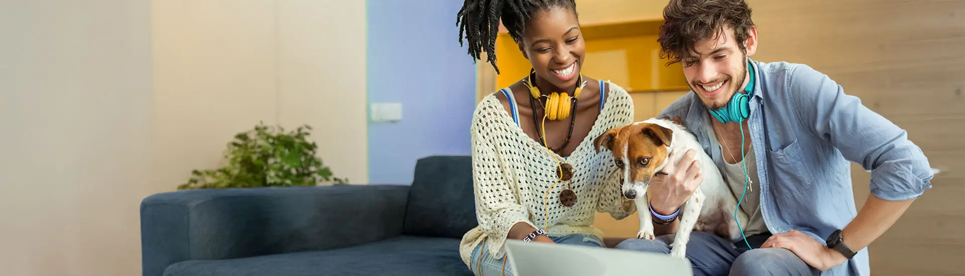A young woman and young man collaborate on a work project. The man is holding his small, cute dog.
